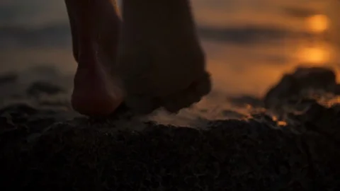 The feet of a young woman walking towards the sea at the first light of dawn Stock Footage