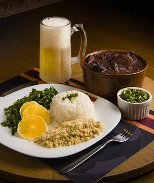 Feijoada stew with farofa, rice, kale and a glass of beer Stock Photos