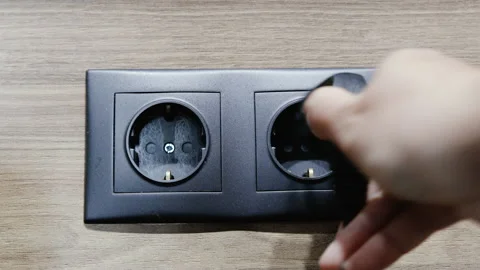 Felame hand inserts the plug into electric socket. Grey plastic power socket and Stock Footage 165173558