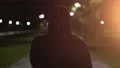 The fellow in a hood walking and smoking on the night street. slow motion 4k or 4k+ Resolution