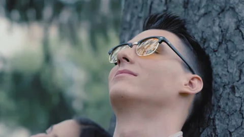 Fellow student is resting in a park under a tree. A student with glasses. Rest Stock Footage 138999110