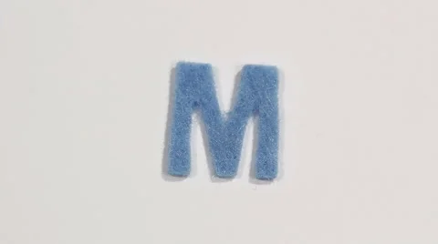 Felt letter “M” on white background. Defocus Stock Footage 60251176