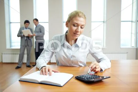 Female accountant working in office with business people in the background Stock Photos