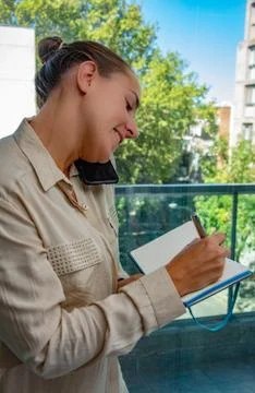 Female administrative assistant taking notes and answering the cell phone Stock Photos