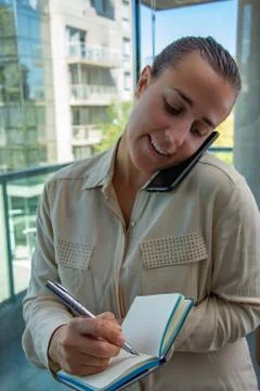 Female administrative assistant taking notes and answering the cell phone Stock Photos