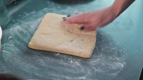 A female adult adjusts a rectangular piece of dough on a countertop covered in Stock Footage 339095801