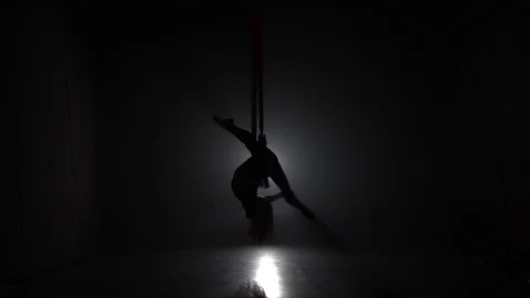 Female aerial gymnast performing on a red silk in a circus stage. Exciting Stock Footage 109047053