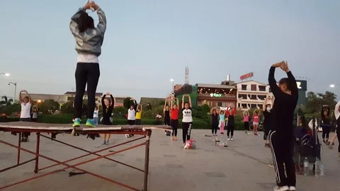 Female aerobics instructors demonstrate in front of class, sundown at Mekong Vídeos de archivo 80636385