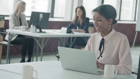 Female afro american manager working in office with laptop, turns around and Stock Footage 124271769