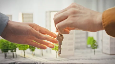 A female agent passes shiny keys to a male client in a light-filled real est Stock Footage 340782566