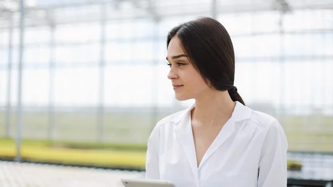 Female agricultural enginee with tablet computer walking along greenhouse Stock Footage 102846653
