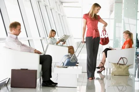 Female airline passenger waiting with other passengers in departure gate Stock Photos