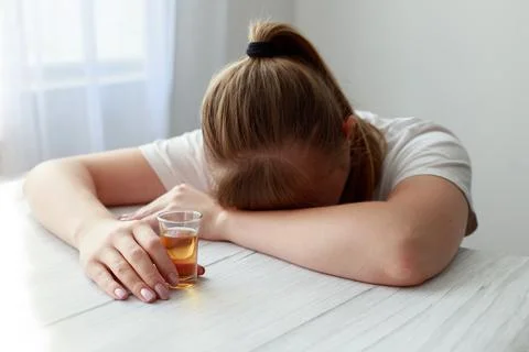 Female alcoholic sleeps on a table with a stack of strong alcohol Stock-Fotos