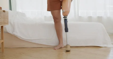 Female amputee is fitting her advanced prosthetic leg in a bright bedroom Stock Footage 335748259
