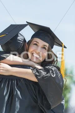 Female and male student embracing on graduation ceremony Stock Photos