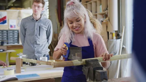 Female Apprentice In Carpentry Workshop For Building Bicycles Frame Sawing Wood Vídeos de archivo 130389506