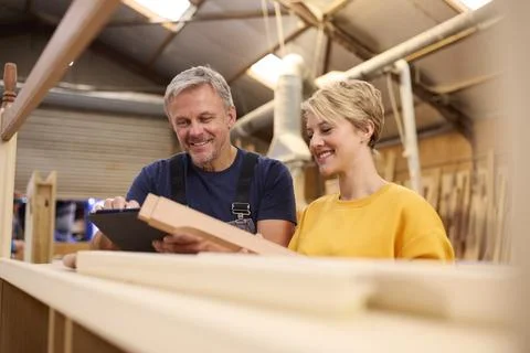 Female Apprentice With Digital Tablet Learning From Mature Male Carpenter In Stock Photos