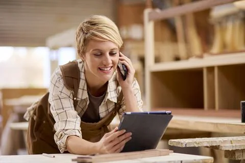 Female Apprentice With Digital Tablet Working As Carpenter In Furniture Workshop 스톡 사진