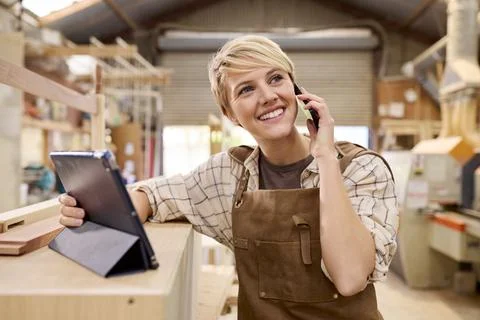 Female Apprentice With Digital Tablet Working As Carpenter In Furniture Workshop 库存照片