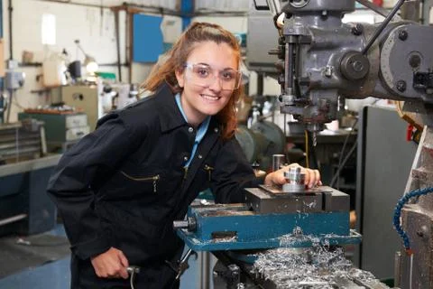 Female Apprentice Engineer Working On Drill In Factory 스톡 사진