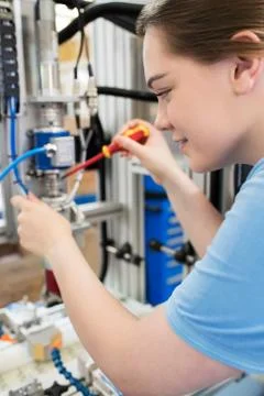 Female Apprentice Engineer Working On Machine In Factory Stock Photos