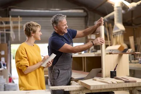 Female Apprentice Learning Skills From Mature Male Carpenter In Furniture Stock Photos