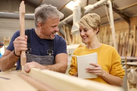 Female Apprentice Learning Skills From Mature Male Carpenter In Furniture Stock Photos