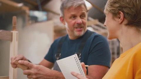 Female Apprentice Making Notes Learning From Mature Male Carpenter In Furniture Stock Footage 242266438