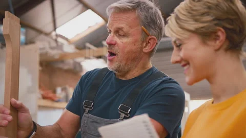 Female Apprentice Making Notes Learning From Mature Male Carpenter In Furniture Stock Footage 242267215