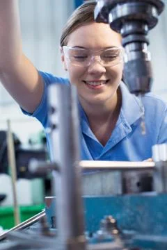 Female Apprentice Using Drill In Factory Stock Photos