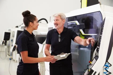 Female Apprentice Working With Engineer On CNC Machinery Foto stock