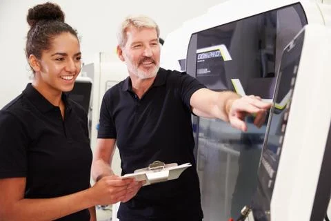 Female Apprentice Working With Engineer On CNC Machinery Foto stock