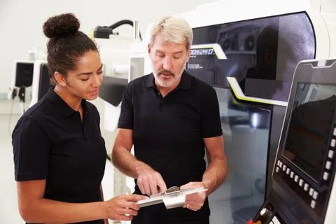 Female Apprentice Working With Engineer On CNC Machinery Foto stock