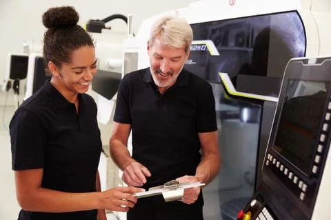 Female Apprentice Working With Engineer On CNC Machinery Foto stock