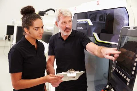 Female Apprentice Working With Engineer On CNC Machinery Foto stock