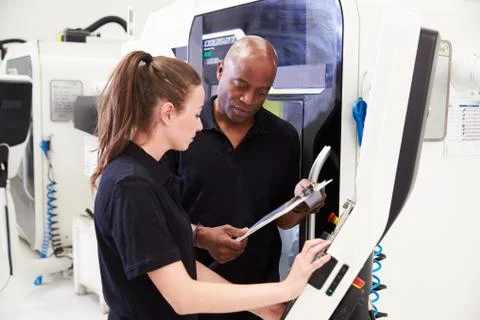 Female Apprentice Working With Engineer On CNC Machinery Foto stock