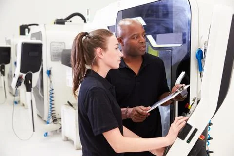 Female Apprentice Working With Engineer On CNC Machinery Foto stock