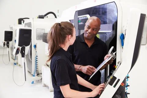 Female Apprentice Working With Engineer On CNC Machinery Foto stock