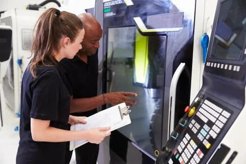 Female Apprentice Working With Engineer On CNC Machinery Foto stock