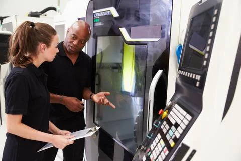 Female Apprentice Working With Engineer On CNC Machinery Foto stock