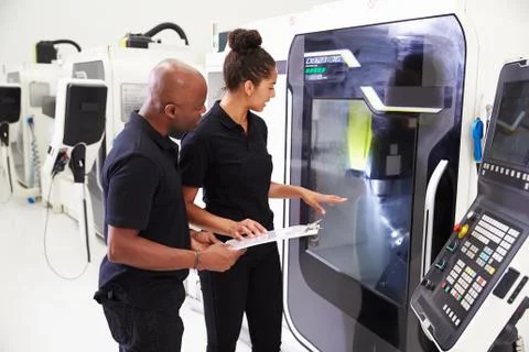Female Apprentice Working With Engineer On CNC Machinery Foto stock