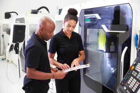 Female Apprentice Working With Engineer On CNC Machinery Foto stock