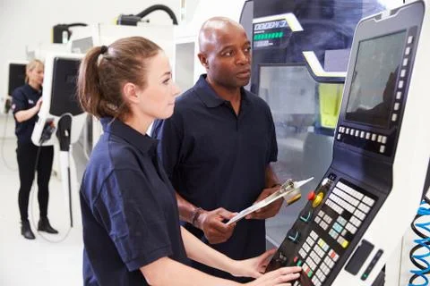 Female Apprentice Working With Engineer On CNC Machinery Foto stock