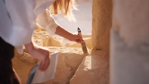 Female archeologist using brush during excavation Stock Footage 166534817
