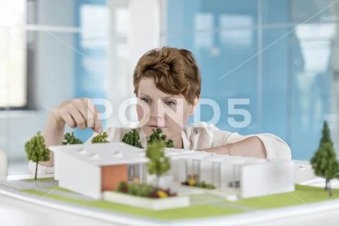 Female architect arranging building model in office Stock Photos