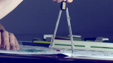 A female architect drawing a circle on a plan with a compass. close up shot Stock Footage 226891588