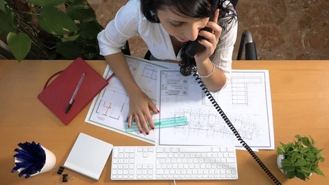 Female architect measuring plan and making appointment answering the phone 動画素材 88337041