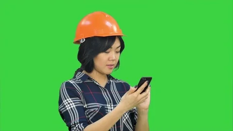 Female architect with orange helmet using smartphone on a Green Screen, Chroma Stock Footage