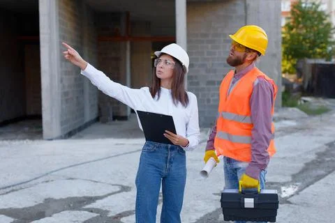 Female architect pointing at something while discussing with construction w.. Stock Photos