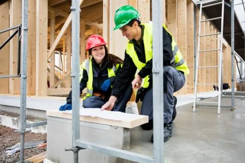 Female Architect Smiling While Sitting By Colleague At Site Stock Photos